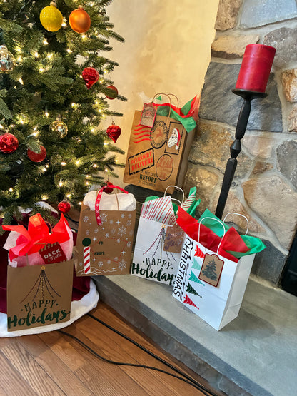 Gift bags with 'Happy Holidays' text near a decorated Christmas tree and stone fireplace.