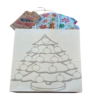 White gift bag with Christmas tree design, filled with wrapped gifts and a 'Merry Christmas' card.